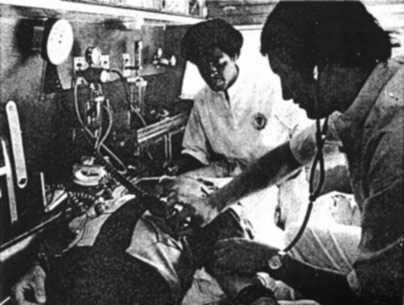 "A black and white photo of two people at work inside of an ambulance"
