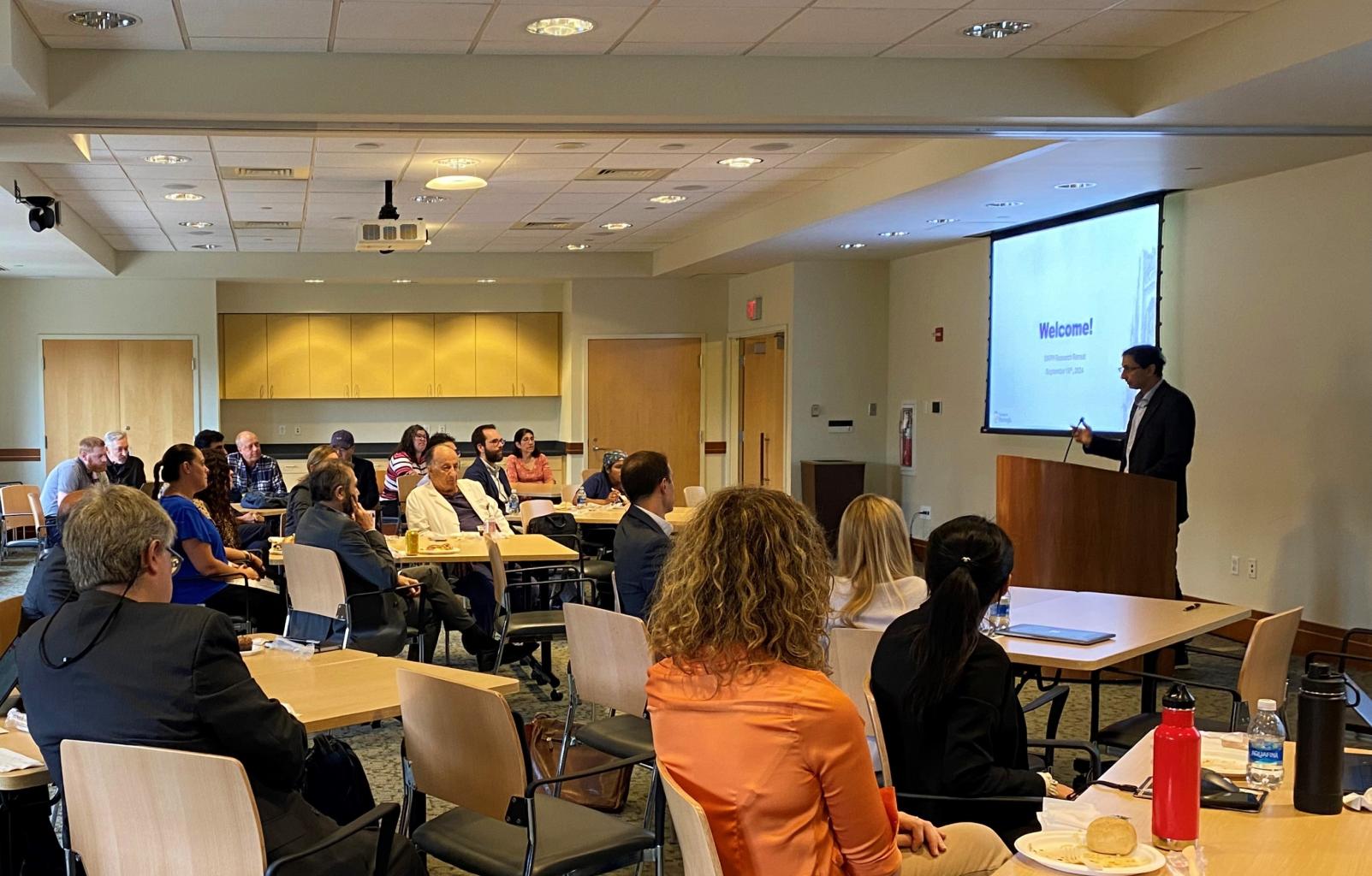 group photo from the 2024 annual research retreat of audience members listening to Dr. Mahajan's presentation