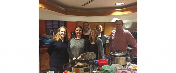 "A group of six CRNAs posing behind table with crock pots and bowls"