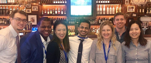 "A group of trainees pose together in front of a bar"