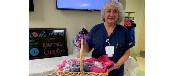 "Cindy McGettigan poses in medical garb with a basket of goods"