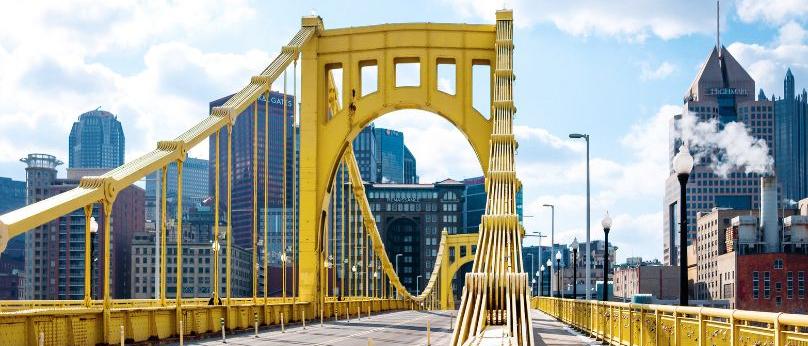 yellow bridge in Pittsburgh on a sunny day with the city skyline in the background