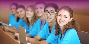 a group of medical trainees in scrubs sitting in front of laptops