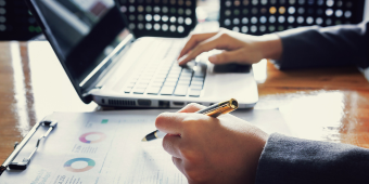 Photo of a person working with a computer and budget sheet