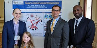 Keith Vogt and Fiona Vogt, Alex Burlew, and Marcus Simmons standing in front of Alex's poster at the symposium